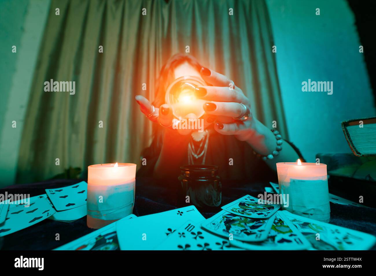 Frau Wahrsagerin errät das Schicksal der Nacht am Tisch mit Kerzen Stockfoto