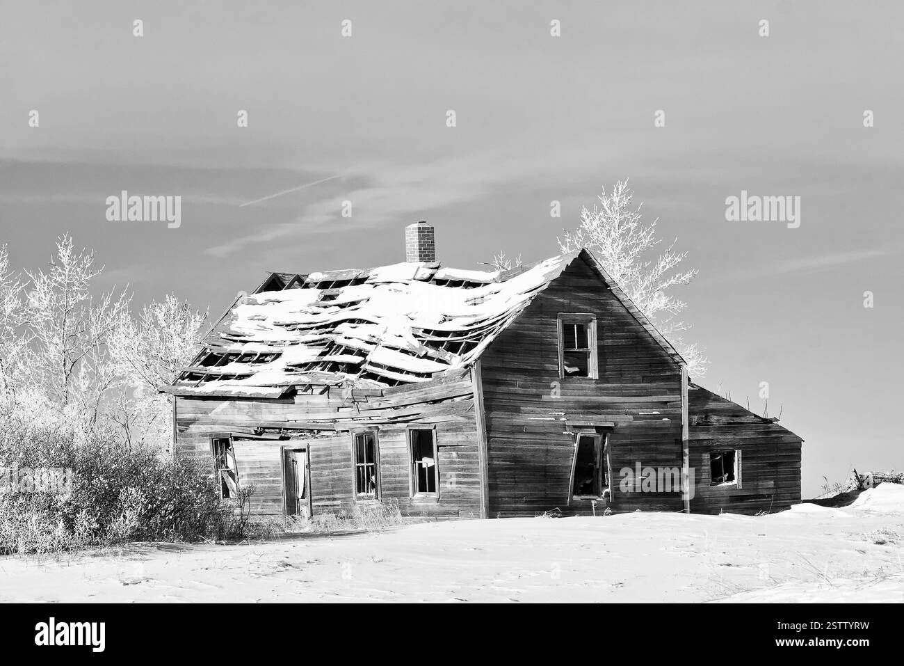 Kleines, altes Haus mit viel Schnee drauf. Das Haus liegt in einer ländlichen Gegend und er ist verlassen Stockfoto