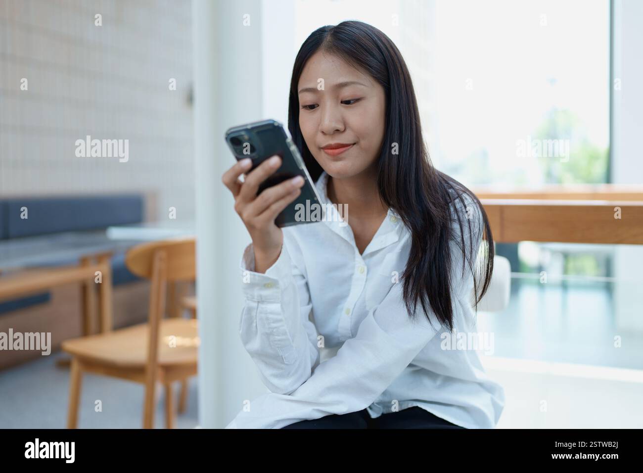 Die Frau saß bequem auf einem Stuhl und genoss einen Moment der Ruhe und Besinnung in ihrem Wohnzimmer. Stockfoto