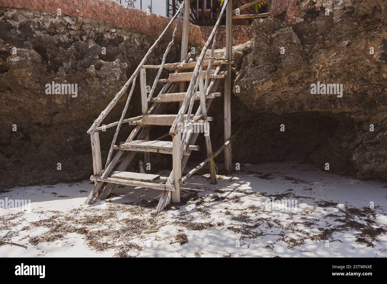 Alte Holztreppe am Strand. Rustikale Leiter in Steinen am tropischen Strand. Alte Treppen auf dem Felsen. Architekturdetails in tropischem Dorf. Stockfoto