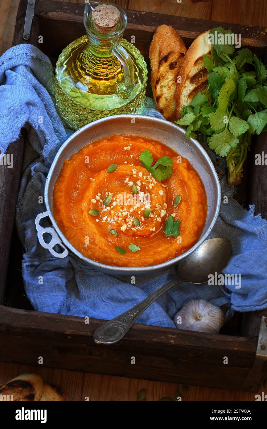 Kürbispüree Suppe mit geröstetem Baguette auf einem Holztablett Stockfoto