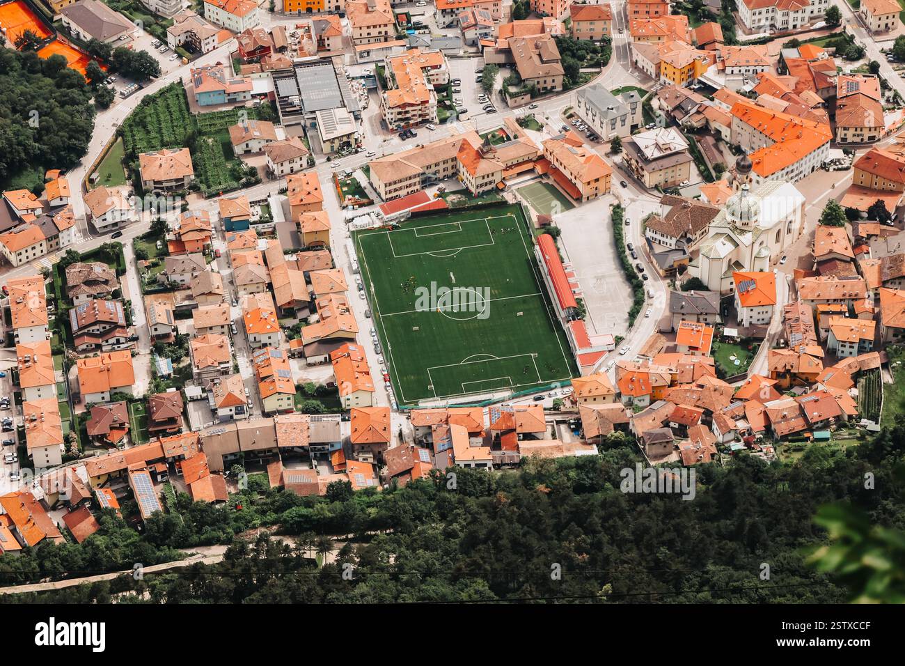 Blick von oben auf ein Sportstadion, umgeben von Häusern mit roten Dächern. Norditalien. Stockfoto