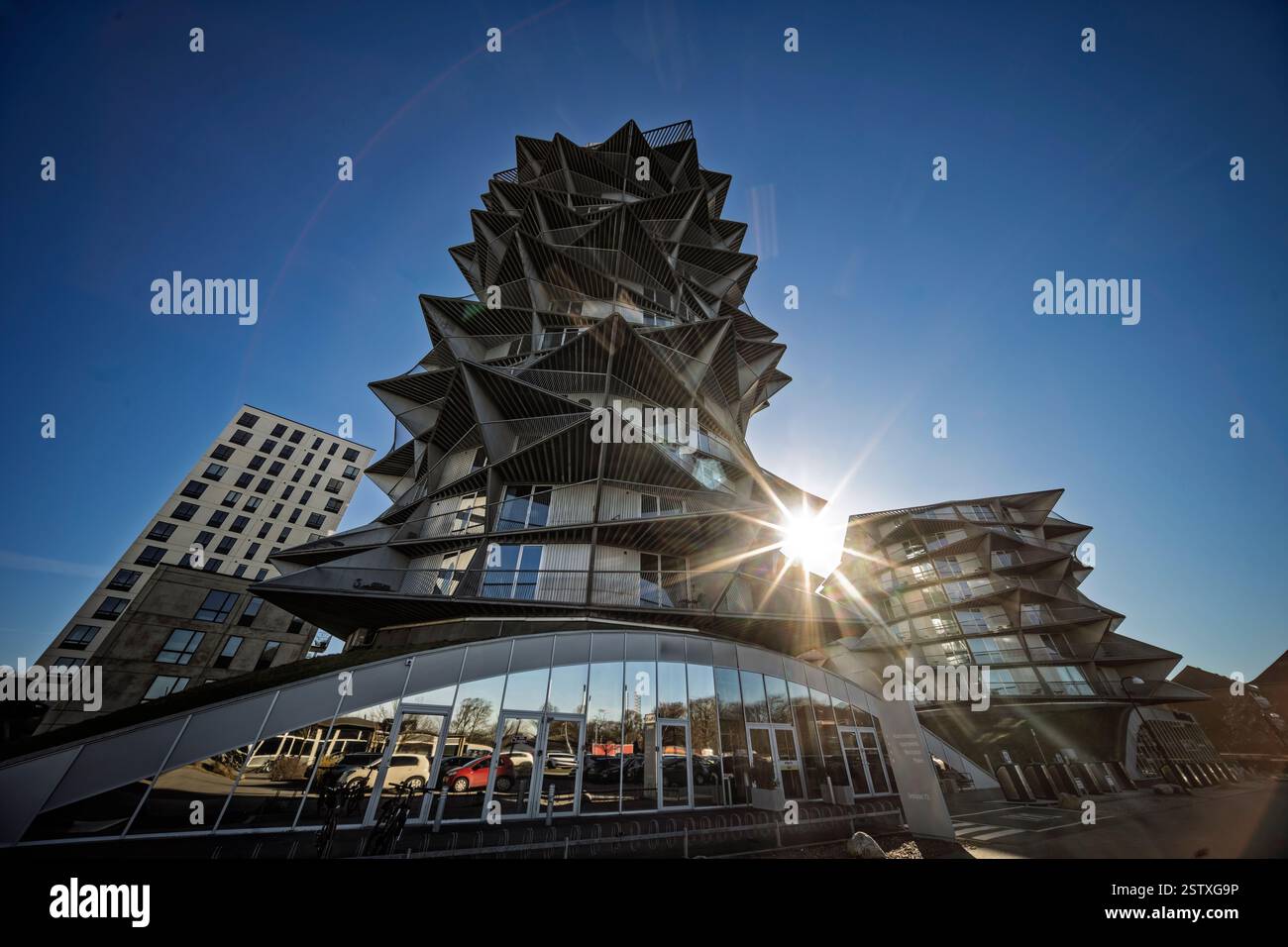Einzigartige und auffallend angewinkelte moderne Architektur vor einem leuchtend klaren blauen Himmel mit innovativem Design und auffälliger urbaner Ästhetik. Stockfoto
