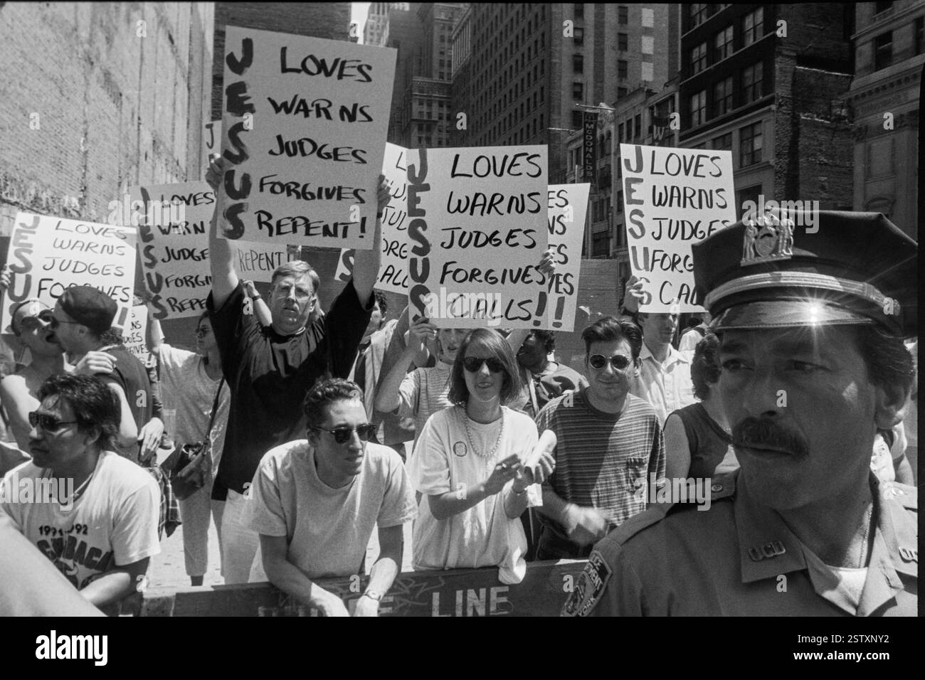 Demonstranten halten Plakate mit religiösen Aussagen hoch, während ein Polizist während des NYC Pride March in New York City, USA am 28. Juni 1992 beobachtet. *** Demonstranten halten Plakate mit religiösen Aussagen hoch, während ein Polizist während des NYC Pride March am 28. Juni 1992 in New York City, USA, beobachtet Stockfoto