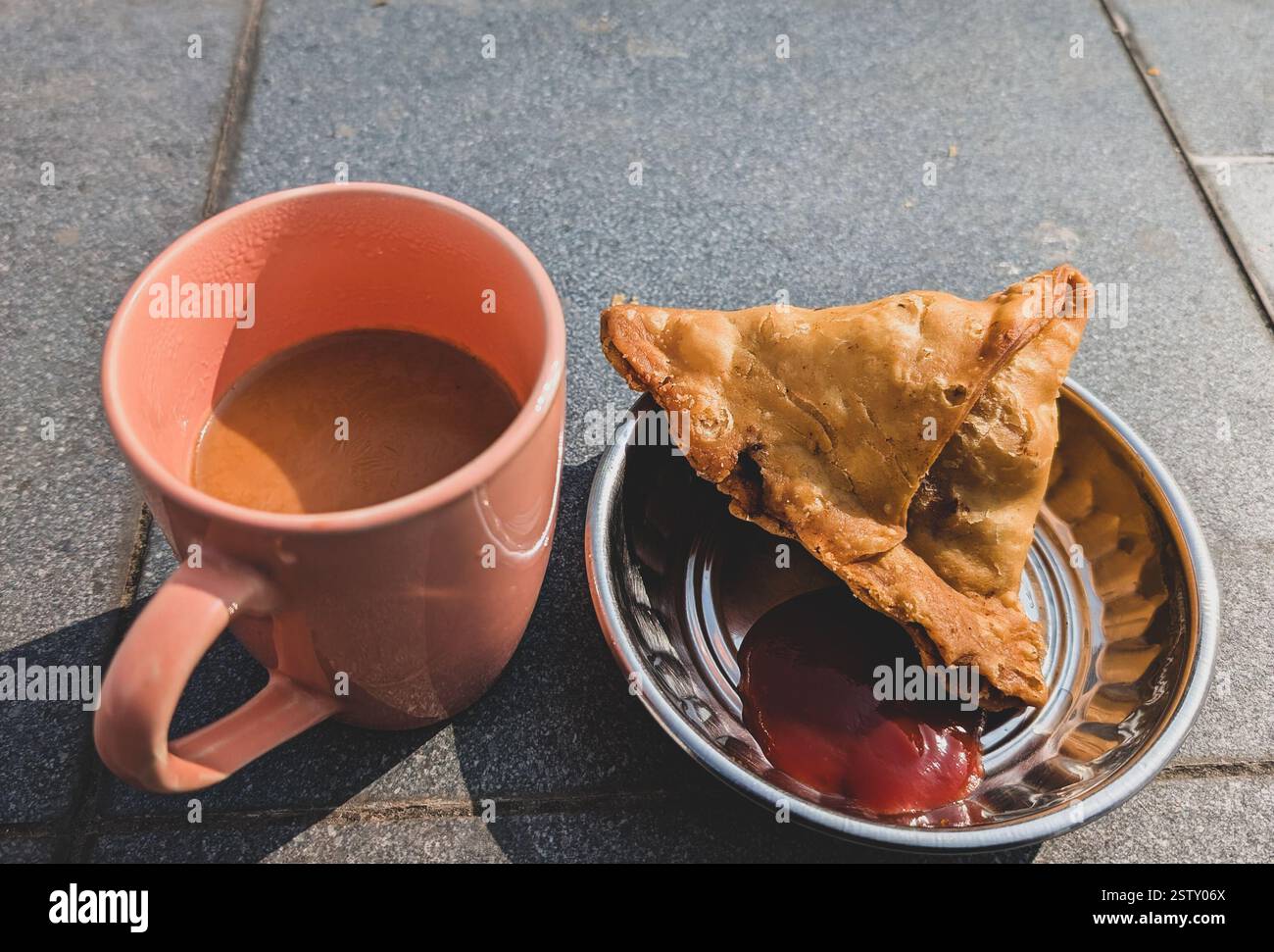 Chai und Samosa, ein beliebtes Snack-Duo in Nordindien, serviert mit würzigem Tamarindenchutney. Ein perfektes Teeerlebnis. Stockfoto