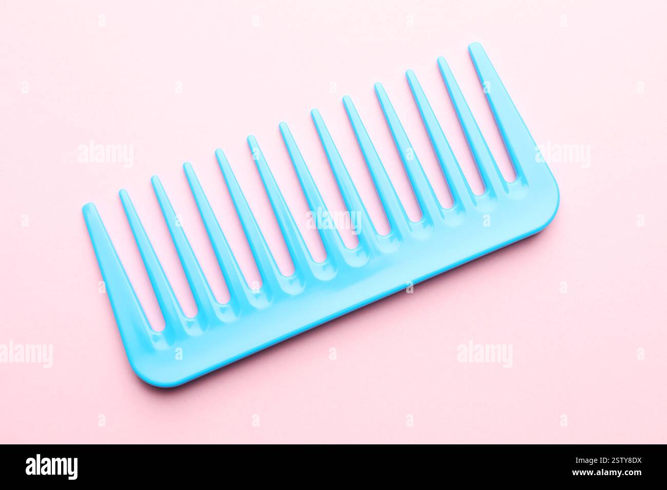 Ein hellblauer Kunststoffkamm auf rosafarbenem Hintergrund, Draufsicht Stockfoto