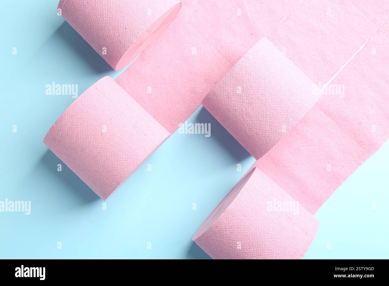 Rosafarbene Toilettenpapierrollen auf hellblauem Hintergrund, Draufsicht Stockfoto