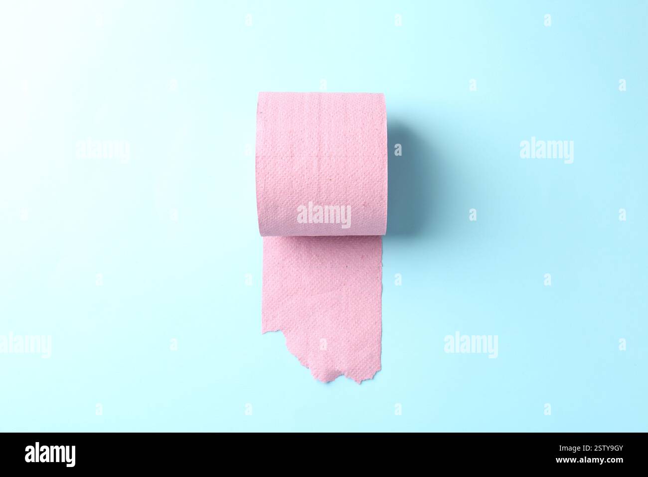 Rosafarbene Toilettenpapierrolle auf hellblauem Hintergrund, Draufsicht Stockfoto