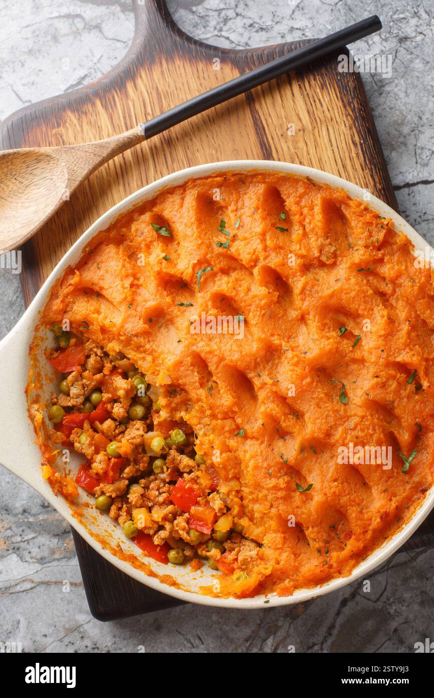 Gesunder Hirtenkuchen aus gemahlenem Fleisch, Gemüse und mit einer Schicht flauschigen süßen Kartoffelpüree in der Nähe auf der Backform auf der Woo Stockfoto