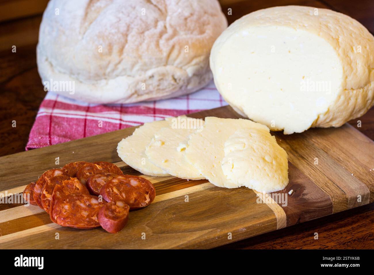 Traditioneller osteuropäischer hausgemachter Käse (Hrudka), serviert auf Holzbrett mit Wurst Stockfoto