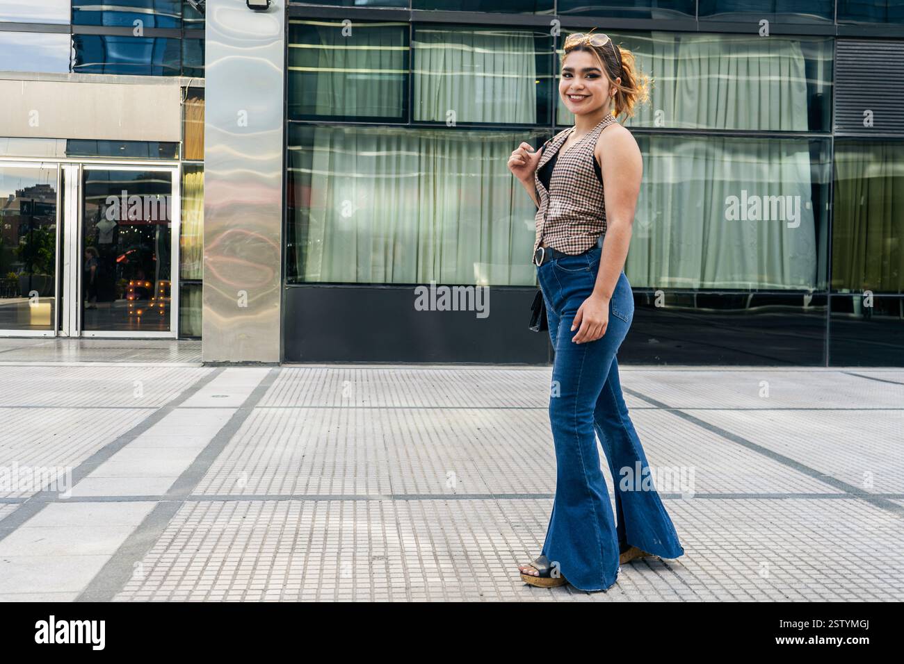 Stilvolle Frau, die vor einem modernen Gebäude schlendert Stockfoto