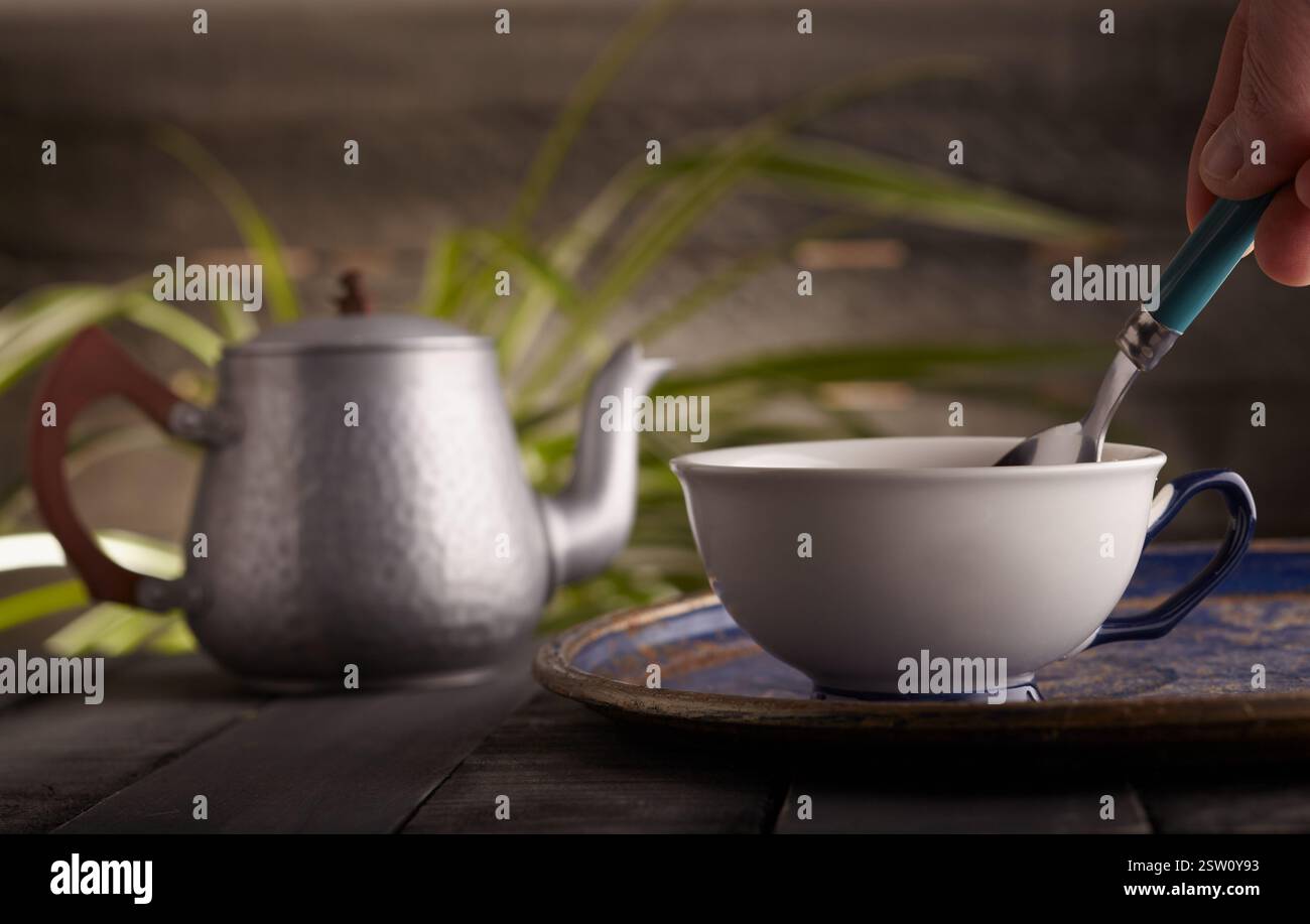 Bone china Teetasse mit Tee und einer Teekanne im Hintergrund. Stockfoto