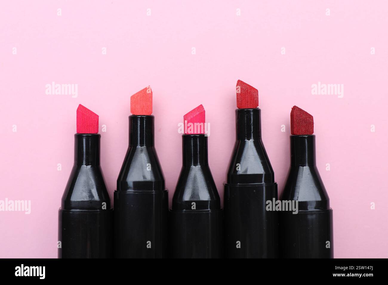 Bunte Markierungen auf hellrosa Hintergrund, Draufsicht. Leerzeichen für Text Stockfoto