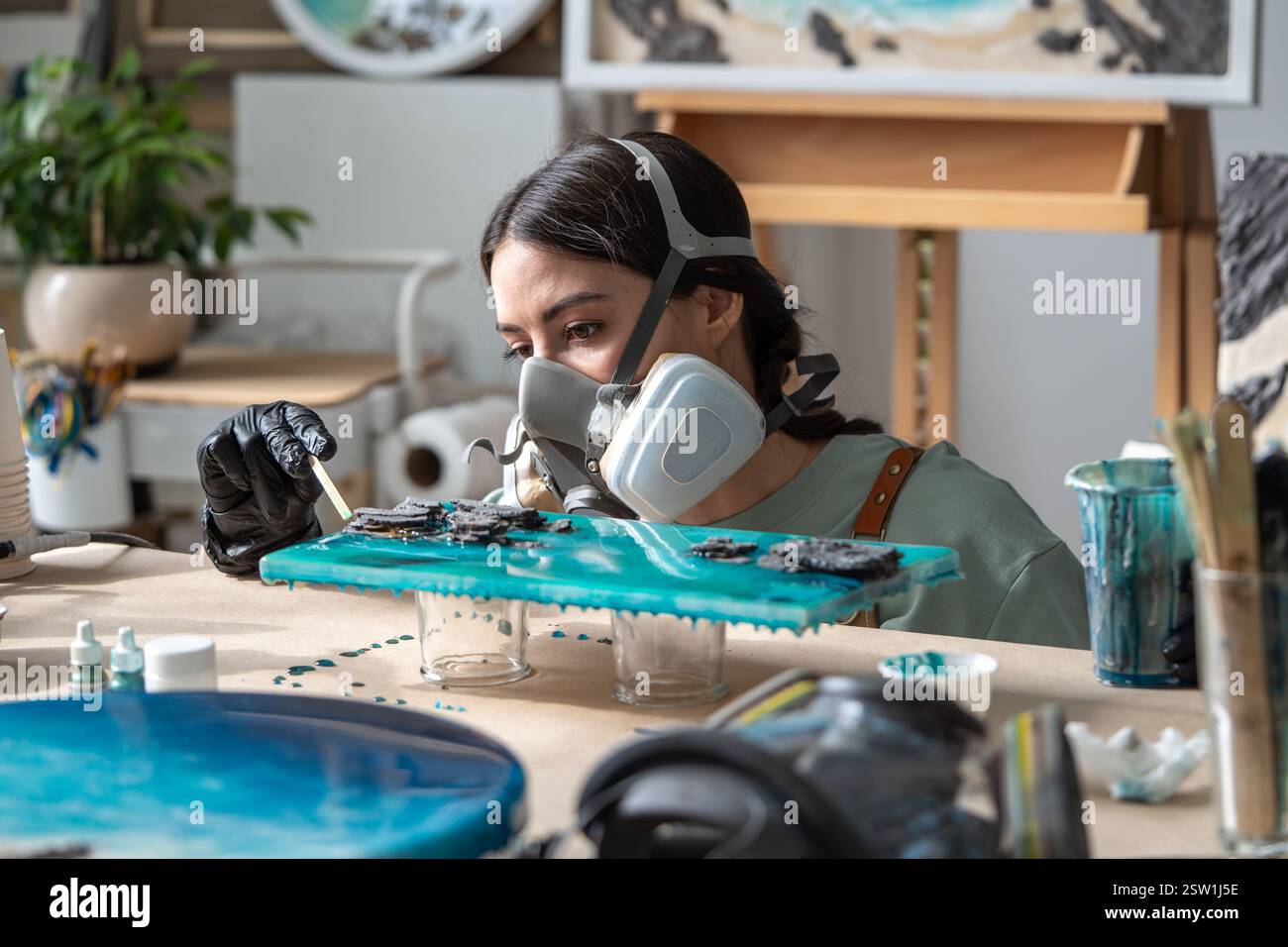 Ernsthaft fokussierte Künstlerin, die mit Epoxidharz arbeitet und auf Details der Malerei achtet. Stockfoto