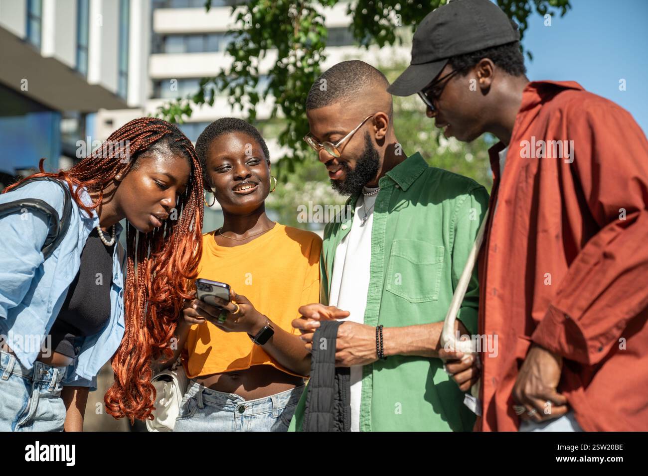 Glücklich interessierte afroamerikanische Freunde nutzen Smartphone Lachen Spaß beim Gehen auf der Straße. Stockfoto