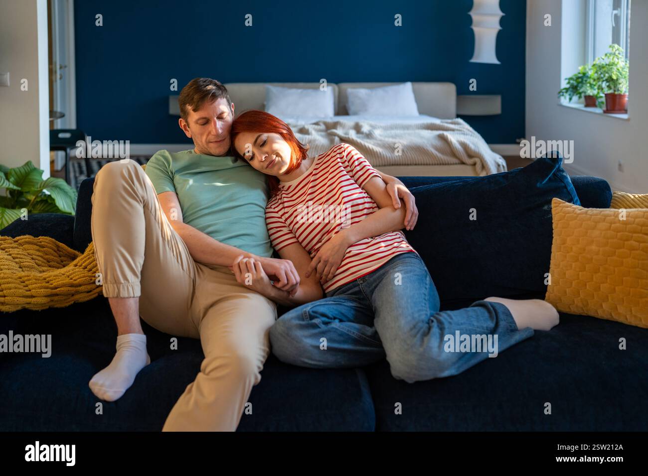 Liebevolles, liebevolles Familienpaar mittleren Alters, das sich zu Hause auf der Couch umarmt. Stockfoto