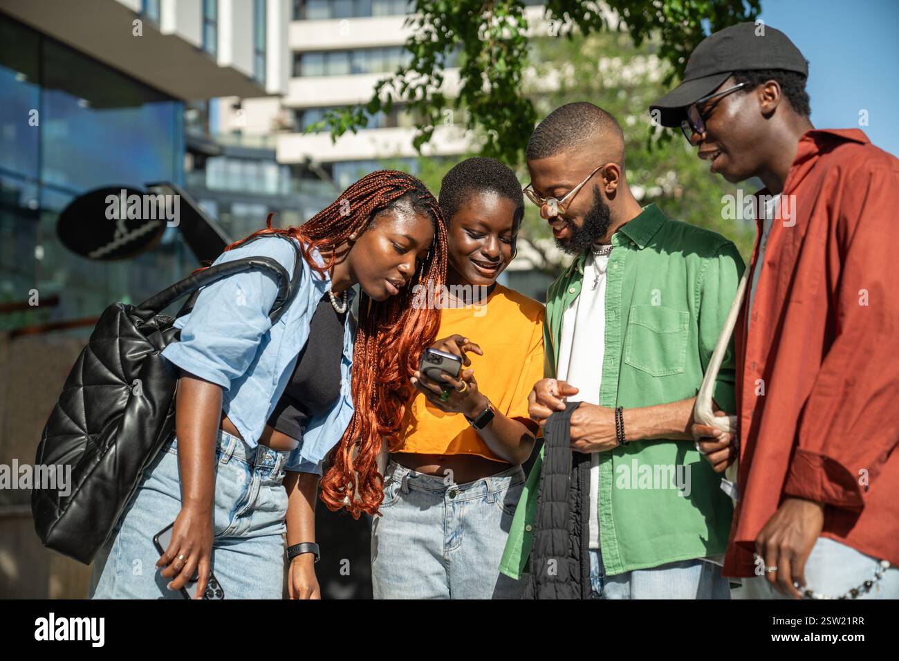 Glücklich interessierte afroamerikanische Freunde nutzen Smartphone Lachen Spaß beim Gehen auf der Straße. Stockfoto