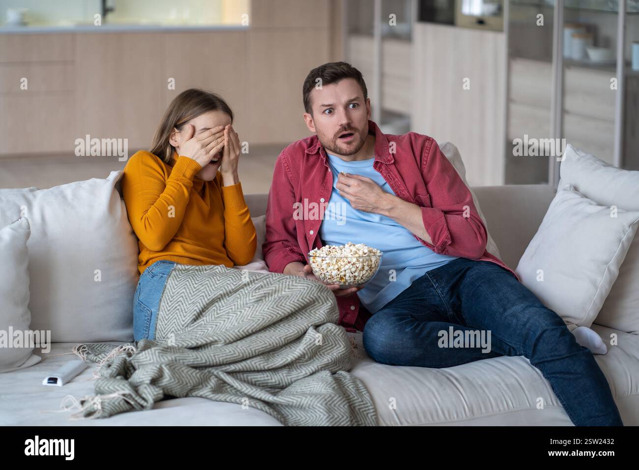 Pärchen, Ehemann, Ehefrau, die sich tagsüber auf dem Sofa im Wohnzimmer entspannen und gemeinsam gruselige Filme anschauen. Stockfoto