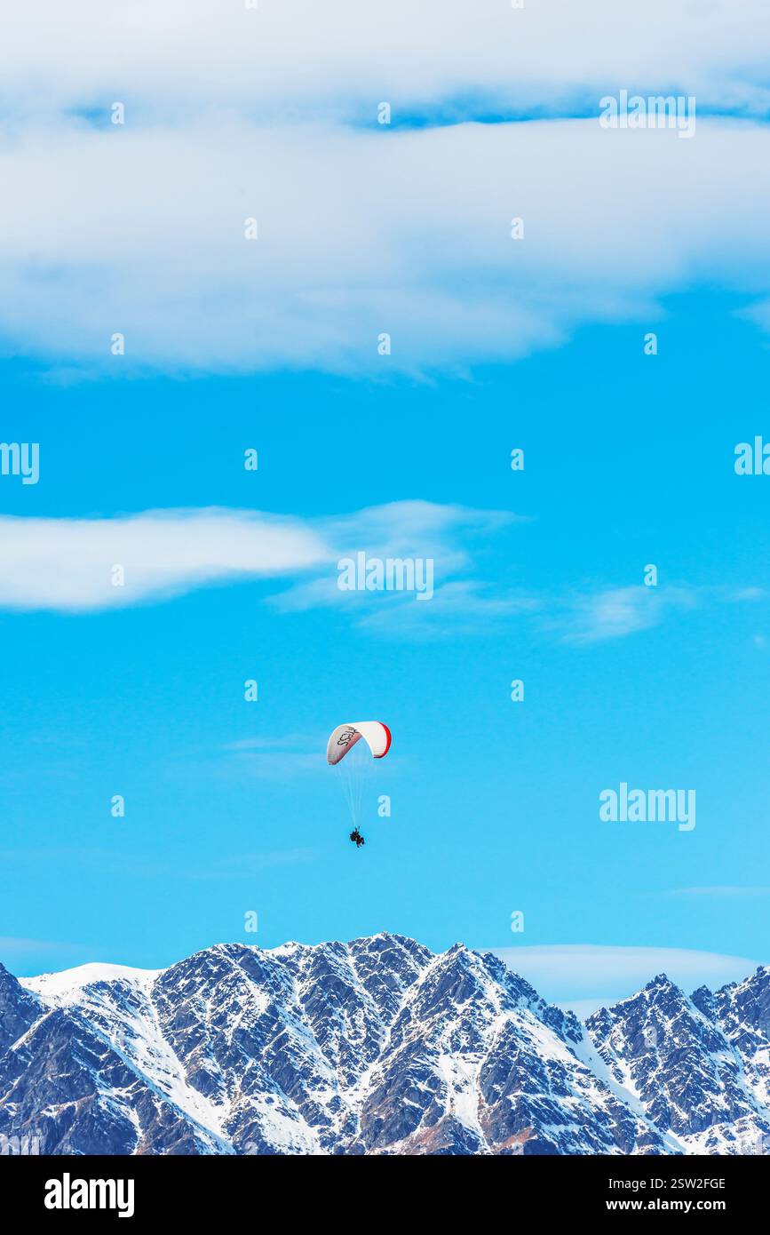 Gleitschirmfliegen über die schneebedeckten Remarkables Bergketten in Queenstown, Südinsel, Neuseeland Stockfoto
