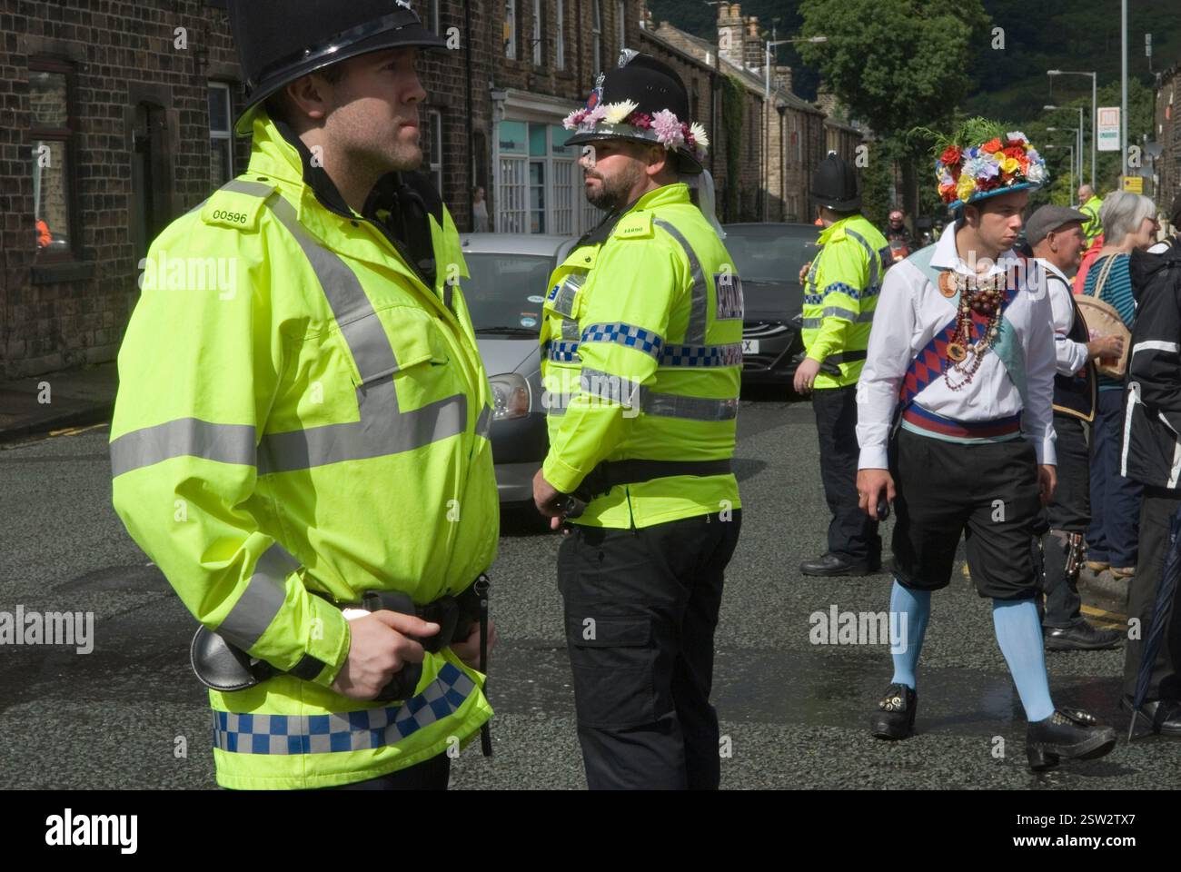 Polizei Großbritannien, Menschenkontrolle, mit Blumen auf ihren Helmen. Sie haben ein Auge auf das Saddleworth Morris Dancing Bank Holiday August Festival Wochenende. Greenfield, Saddleworth, Lancashire England 2012 2010er Jahre, Großbritannien HOMER SYKES Stockfoto