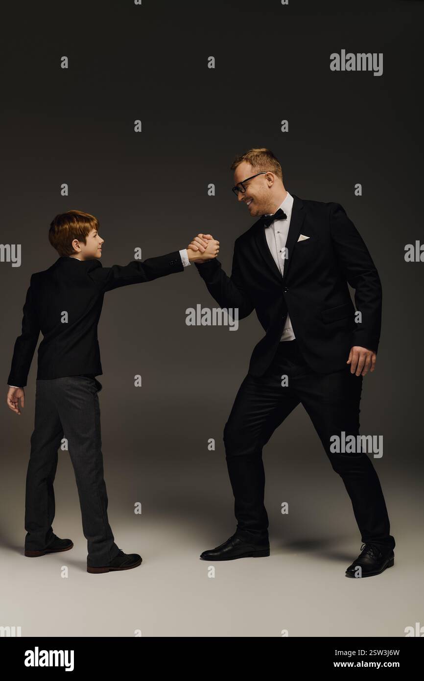 Ein stilvoller Vater und Sohn treten in einem lustigen Armwrestling-Match ein und zeigen ihre Verbundenheit. Stockfoto