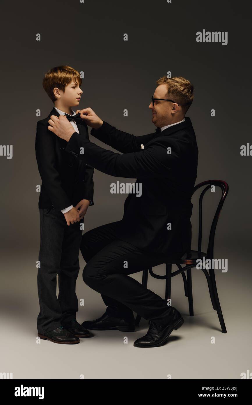 Ein stolzer Vater passt die Fliege eines Sohnes in einem stilvollen Studio an, um einen besonderen Moment festzuhalten. Stockfoto