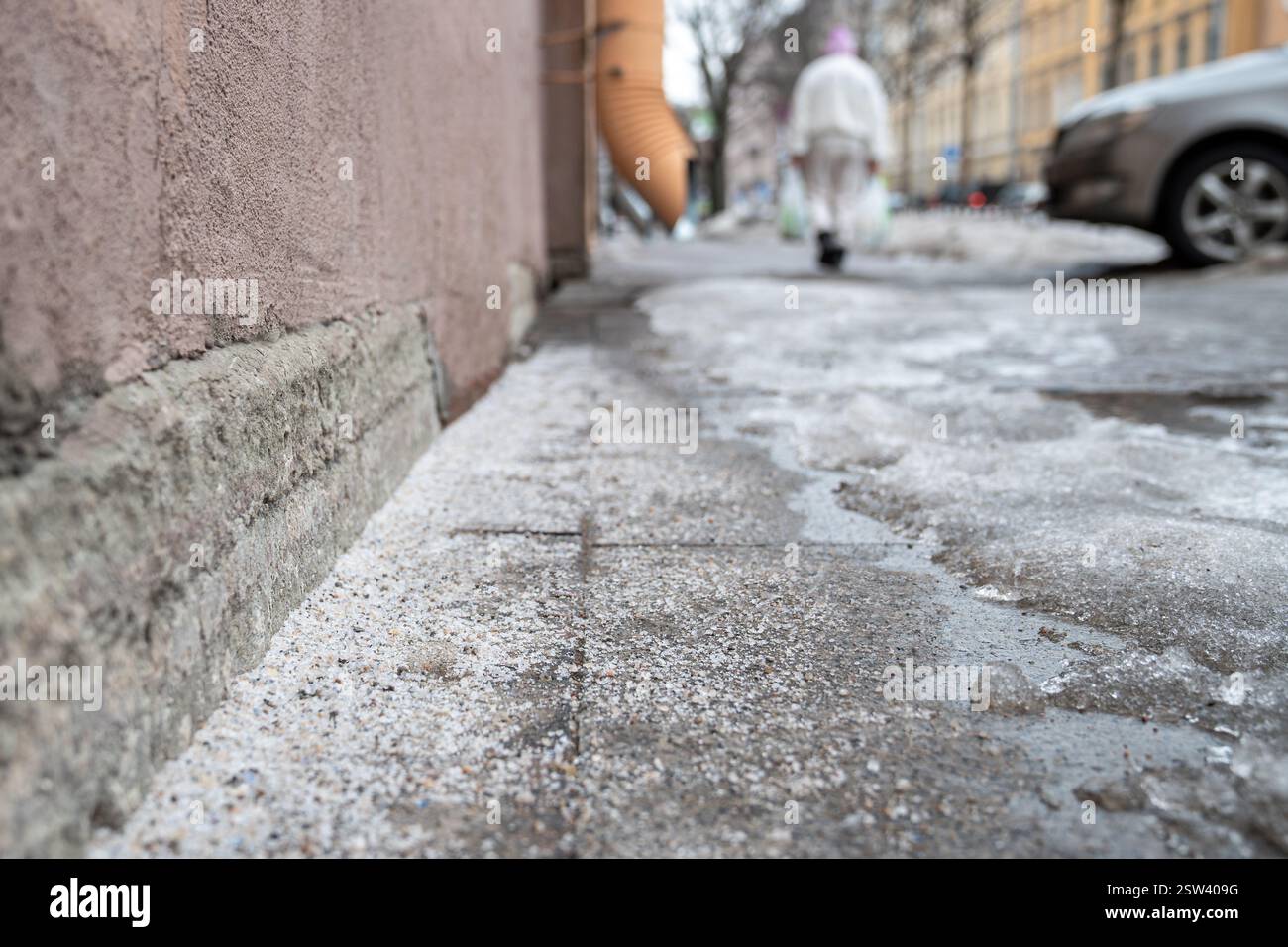 Technische Salzkörner auf vereistem Gehsteig im Winter zum Schmelzen von Eis und Schnee Stockfoto