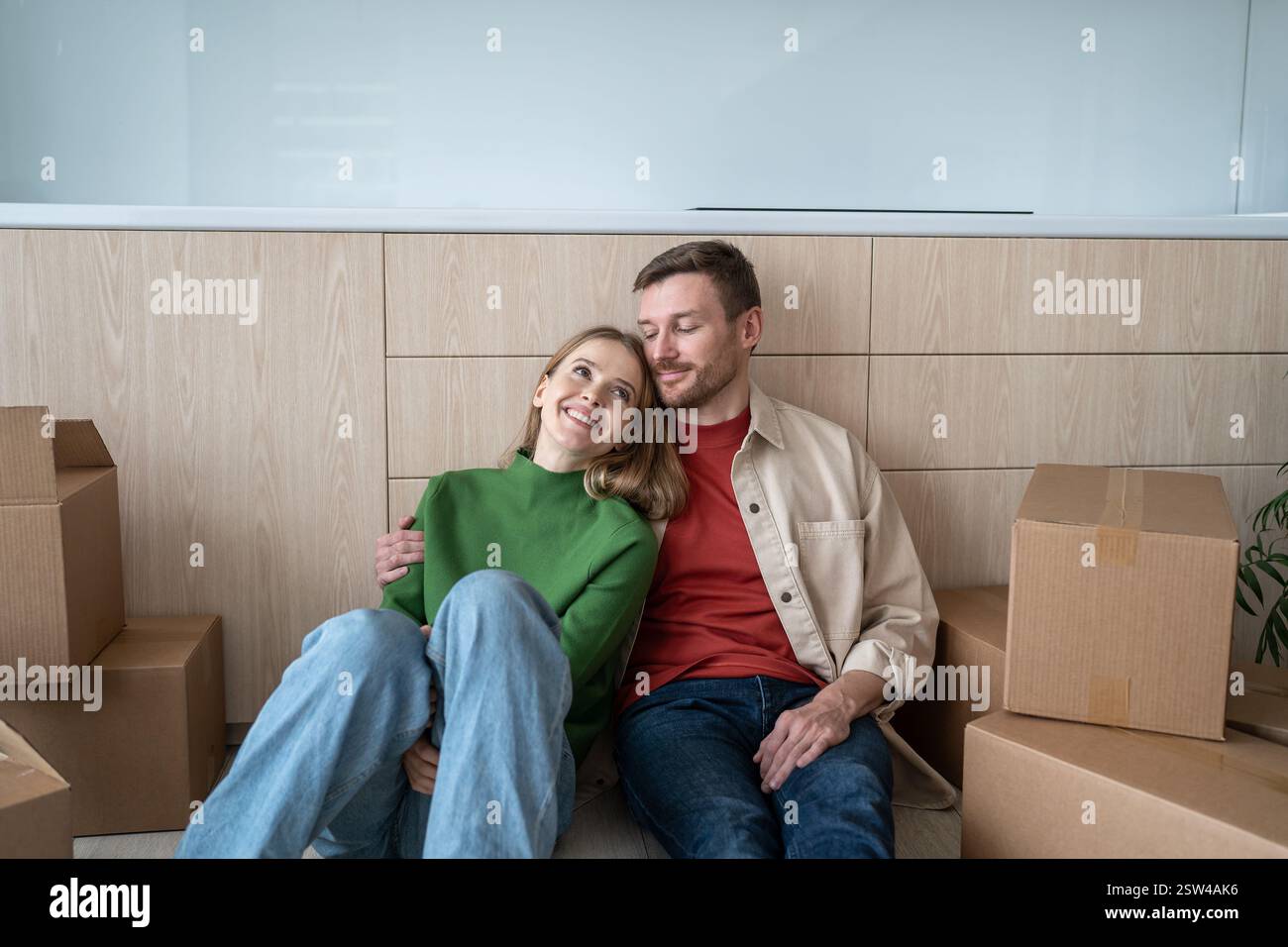 Glückliches Paar Mann Frau, die vom Leben in einer neuen Wohnung träumt, die auf dem Boden sitzt Stockfoto