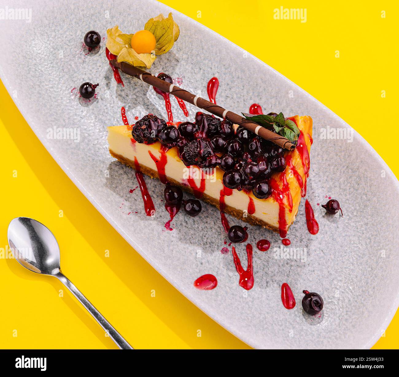 Köstliches Stück Käsekuchen mit schwarzer Johannisbeere und Erdbeersauce Stockfoto