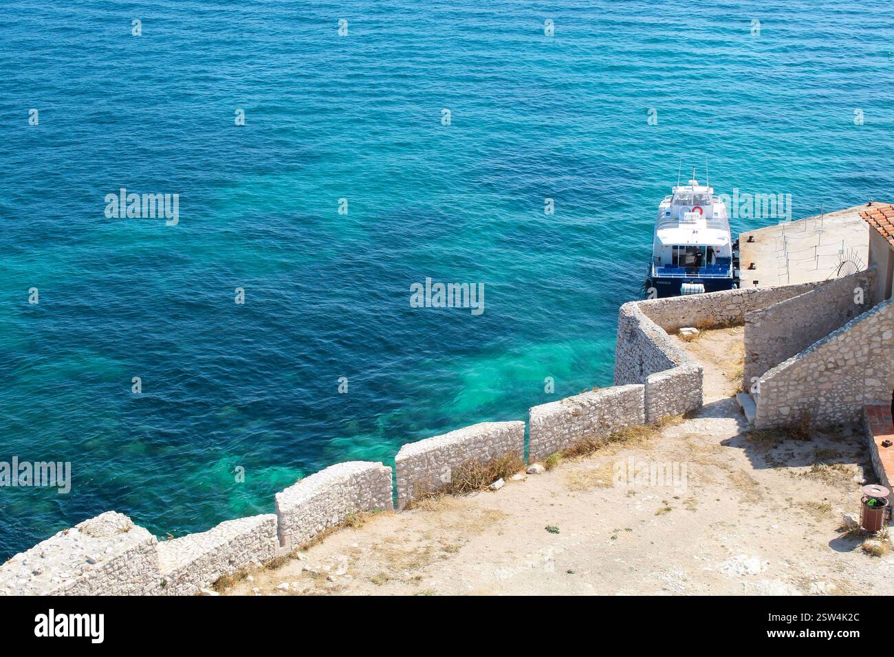 Malerische mediterrane Bucht mit Segelboot – Frankreich. Ein atemberaubender Blick auf eine mediterrane Bucht mit türkisfarbenem Wasser, zerklüfteten Klippen und einem Segelboot. Stockfoto