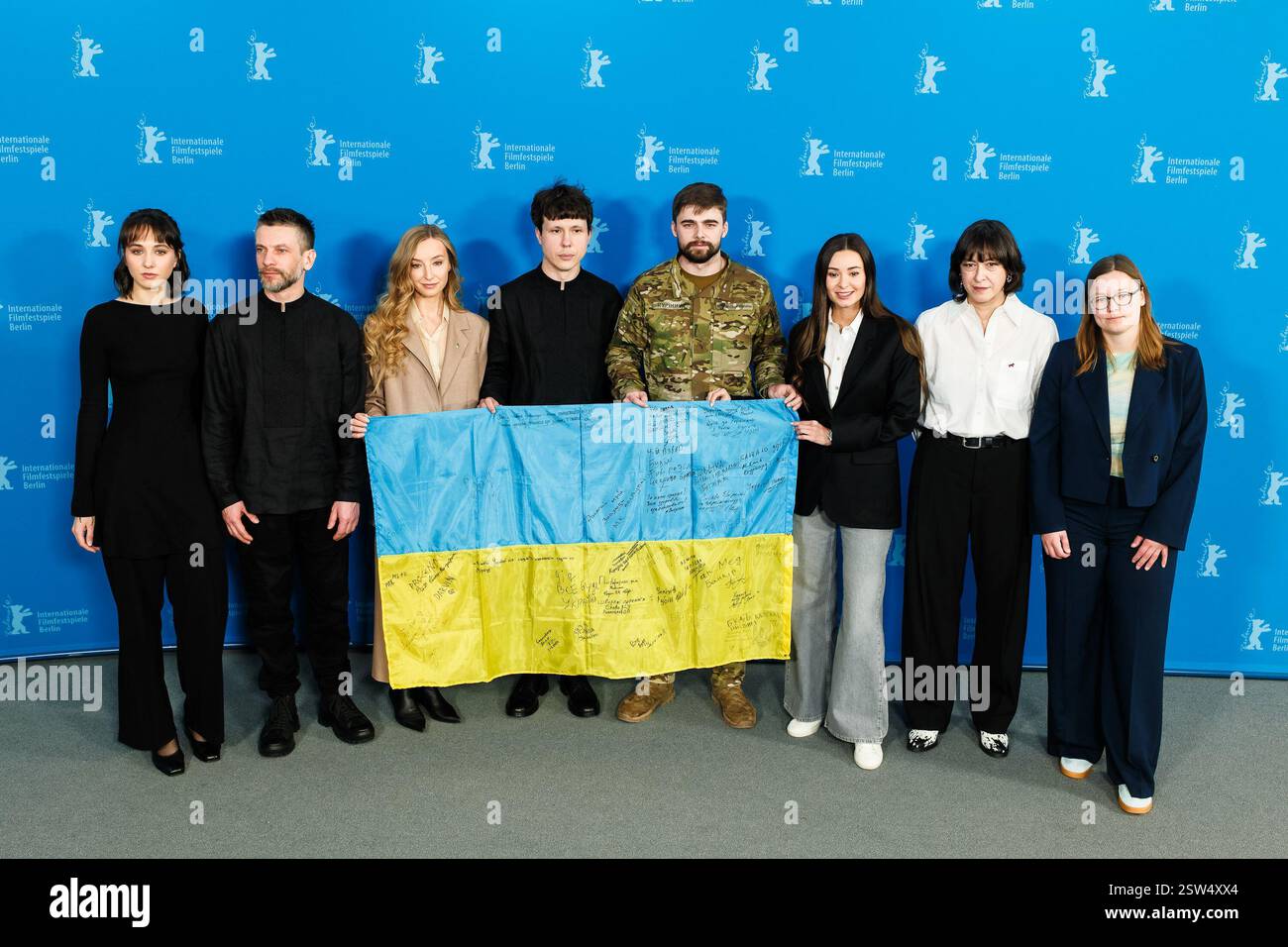Berlin, Deutschland. Februar 2025. Mitglieder der Besetzung und Crew posieren mit einer ukrainischen Flagge, die die Unterschriften von Lehrern trägt, die in den Krieg gezogen sind, wie sie beim Fotoruf für Timestamp während der Berlinale im Grand Hyatt Berlin zu sehen waren. Foto von Julie Edwards./Alamy Live News Stockfoto