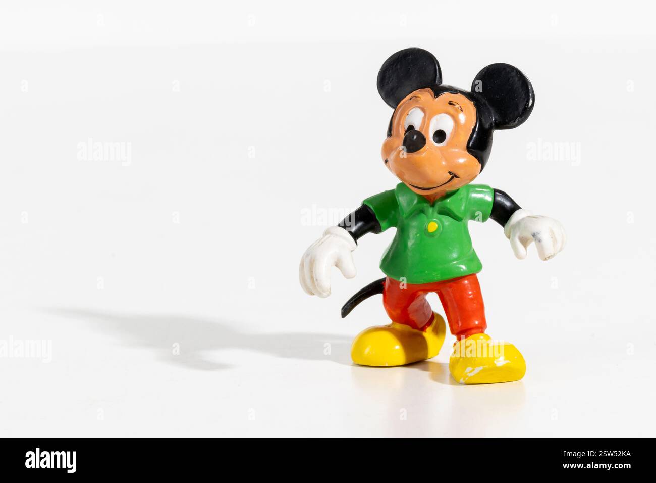 Kleine Vintage Mickey Maus Figur mit grünem Hemd und roter Hose auf weißem Hintergrund Stockfoto