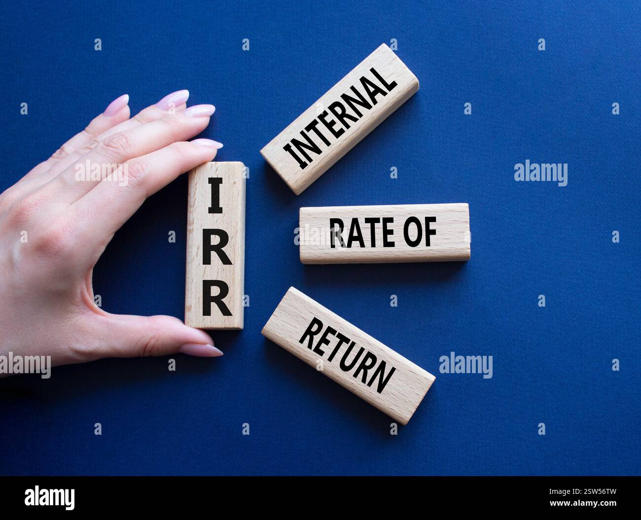 IRR – Symbol für interne Rückkehrrate. Konzeptwort IRR auf Holzwürfeln. Geschäftsmann Hand. Wunderschöner tiefblauer Hintergrund. Business und IRR-Konzept. Co Stockfoto