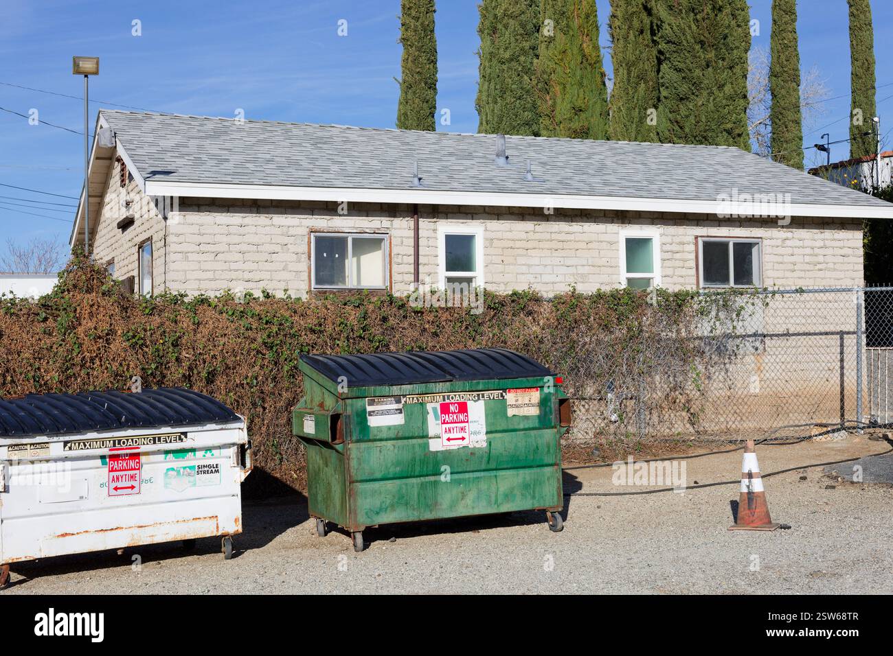 Braunes Backsteingebäude und zwei gewerbliche Mülltonnen. Stockfoto