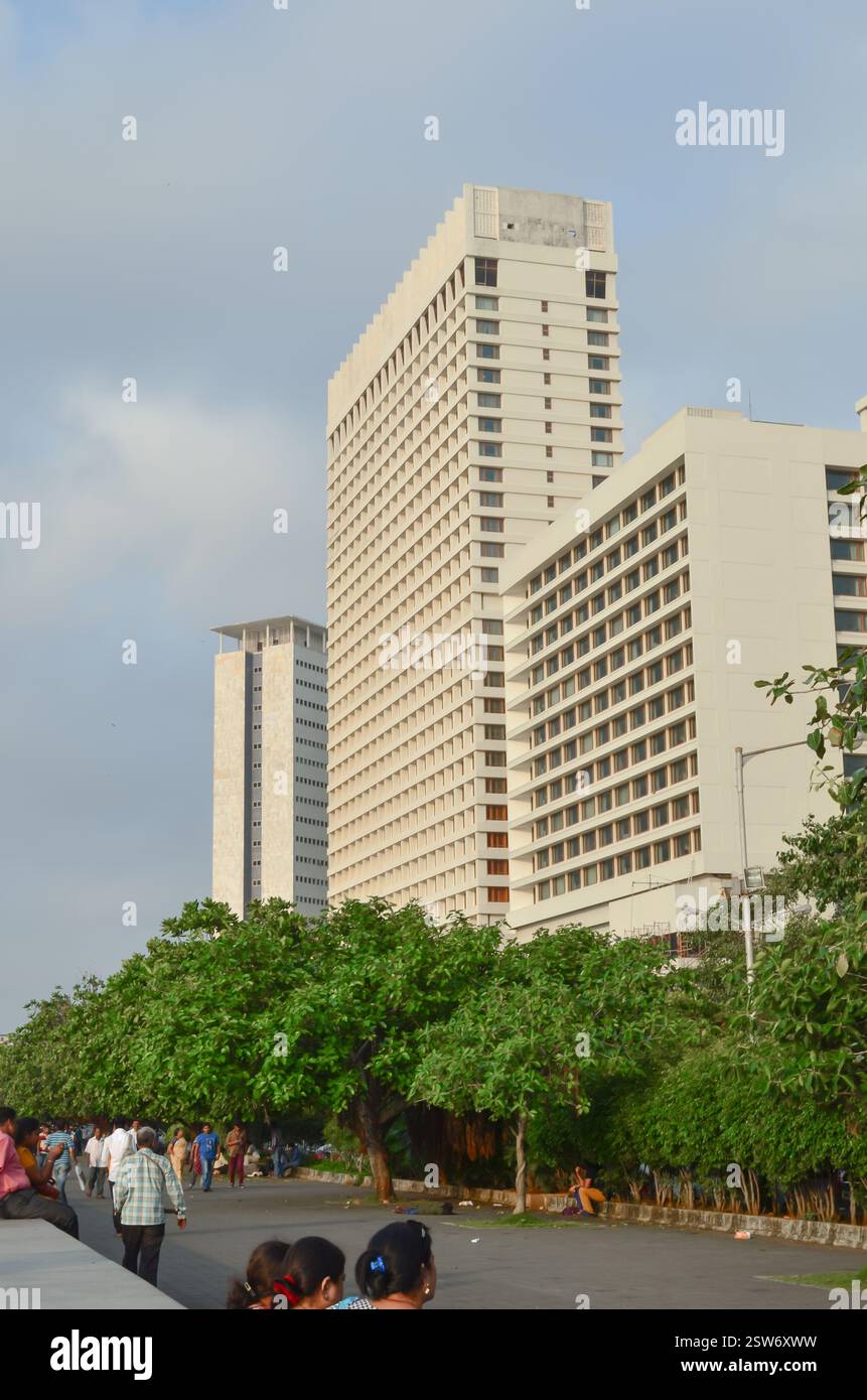 Moderne Hochhaus-Hotelgebäude ragen über grüne Bäume und Fußgänger entlang der Marine Drive in Nariman Point, Süd-Mumbai. Stockfoto