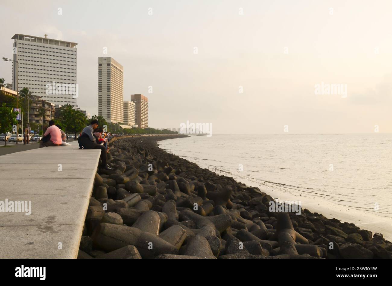 Menschen, die sich entlang der Marine-Drive-Promenade neben den Tetrapoden-Wellenbrecheranlagen entspannen und auf den Arabischen Meerbusen in Süd-Mumbai blicken. Stockfoto
