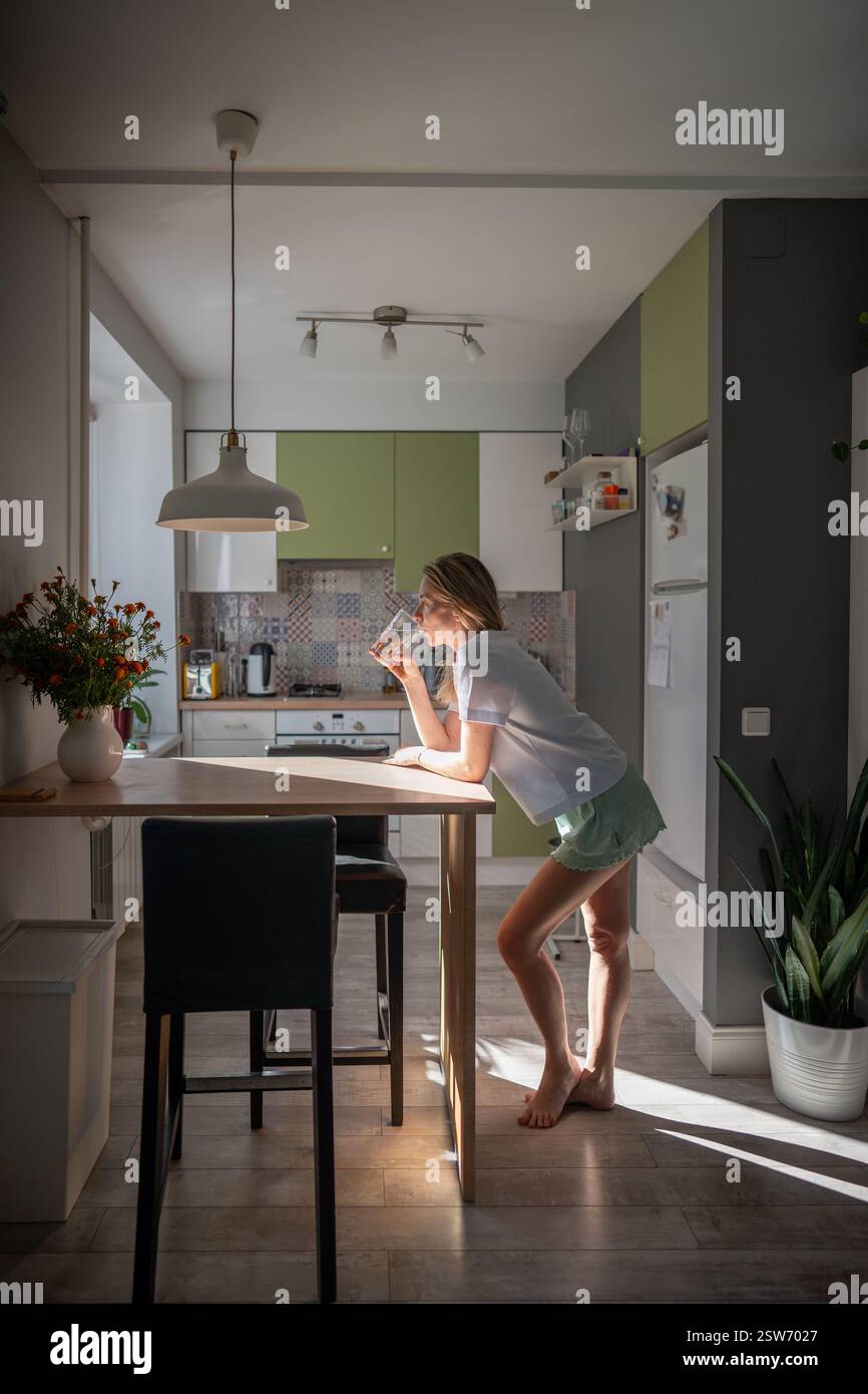 Ruhige gesunde morgendliche Routine der Frau trinkt Glas Wasser nach dem Aufwachen, stehend auf der Küche zu Hause Stockfoto