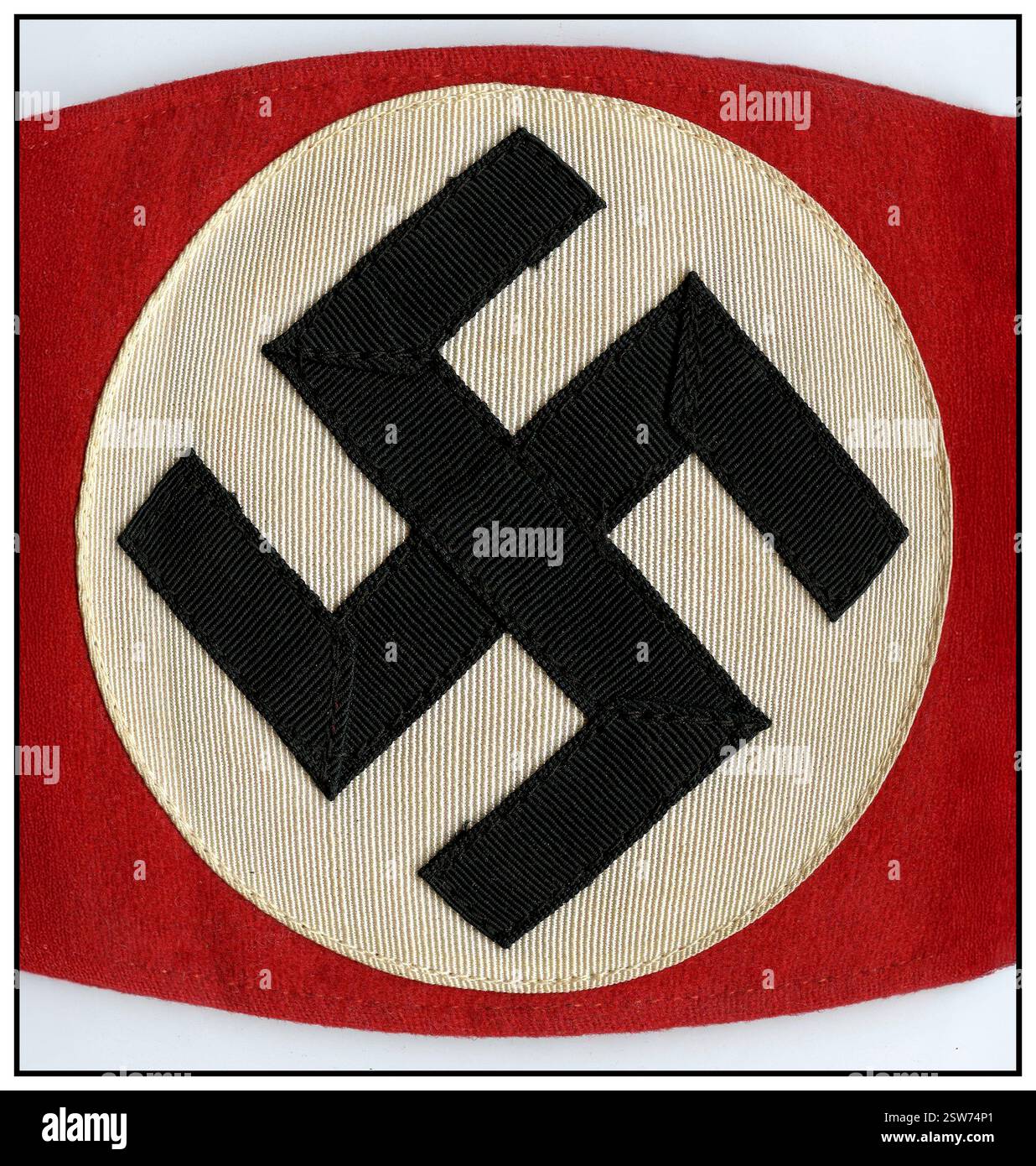 Das Hakenkreuz-Armband ist ein Kleidungsstück mit dem Hakenkreuz – einem Symbol mit alten Wurzeln, das von der NSDAP in den 1930er Jahren und während des Zweiten Weltkriegs berüchtigt wurde. Unter der Herrschaft der Nazis wurde dieses Symbol zu einem Schlüsselelement der Propaganda, das verwendet wurde, um die rassistische und faschistische Ideologie des Regimes zu repräsentieren. Heute ist das Hakenkreuz weithin als Hasssymbol anerkannt, da es mit den abscheulichen Gräueltaten der NS-Zeit in Verbindung gebracht wird Stockfoto