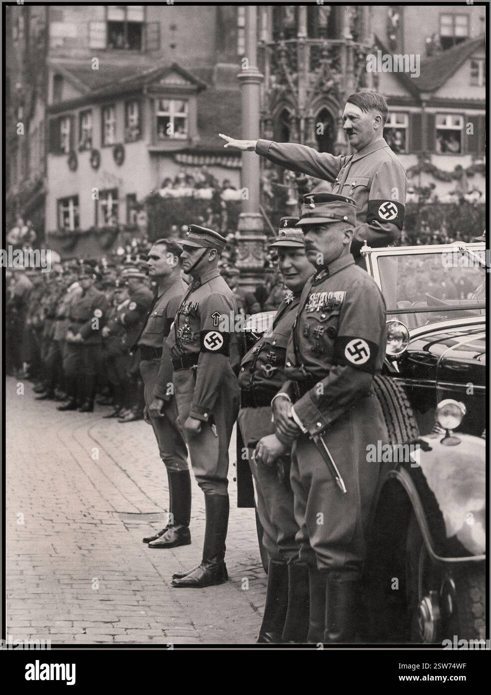 ADOLF HITLER Vintage Nürnberger Rallye 1935, Deutschland - SA Sturmabteilung politische Milizen der NSDAP, marschieren bei einer Parade in der Stadt an Adolf Hitler vorbei. Adolf Hitler aus den 1930er Jahren trug Hakenkreuzarmband bei einer Militärparade und stand in seinem Mercedes-Wagen mit Heil Hitler-Gruß an die vorbeiziehenden Sturmabteilungstruppen Hermann Goring und Rudolf Hess im Vordergrund Nürnberger Nazi-Deutschland Stockfoto