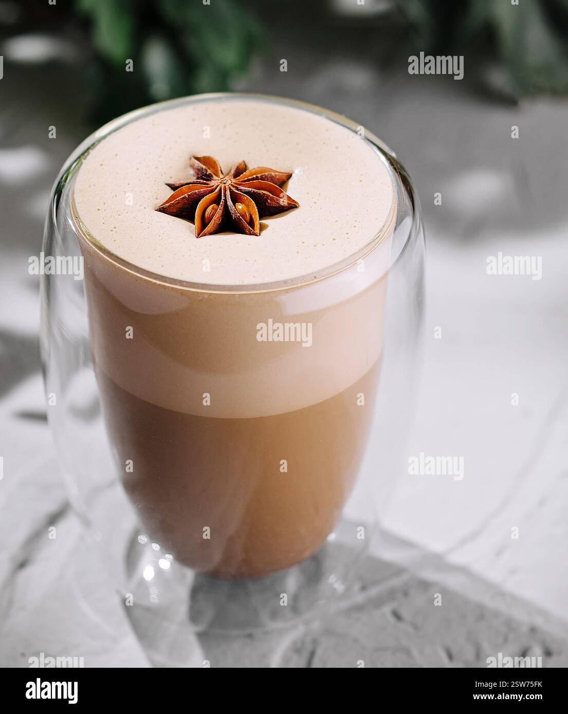 Gewürzter Latte in einem transparenten Glas auf strukturierter Oberfläche Stockfoto