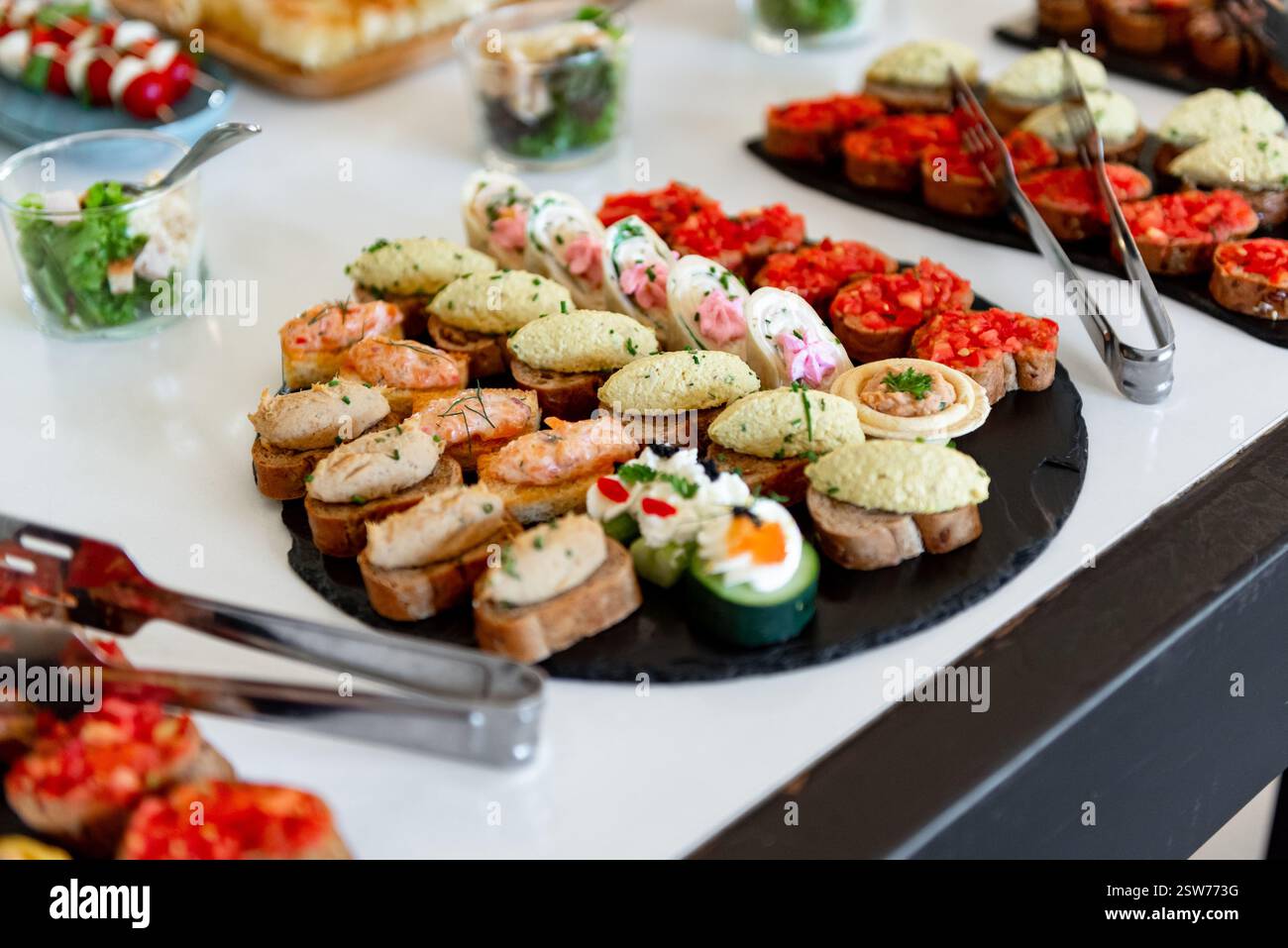 Farbenfrohe Kanapees, die kunstvoll auf einem eleganten Display angeordnet sind, laden Gäste zu einer lebhaften Feier ein, die eine Mischung aus Aromen und Texturen für die Gäste bietet Stockfoto