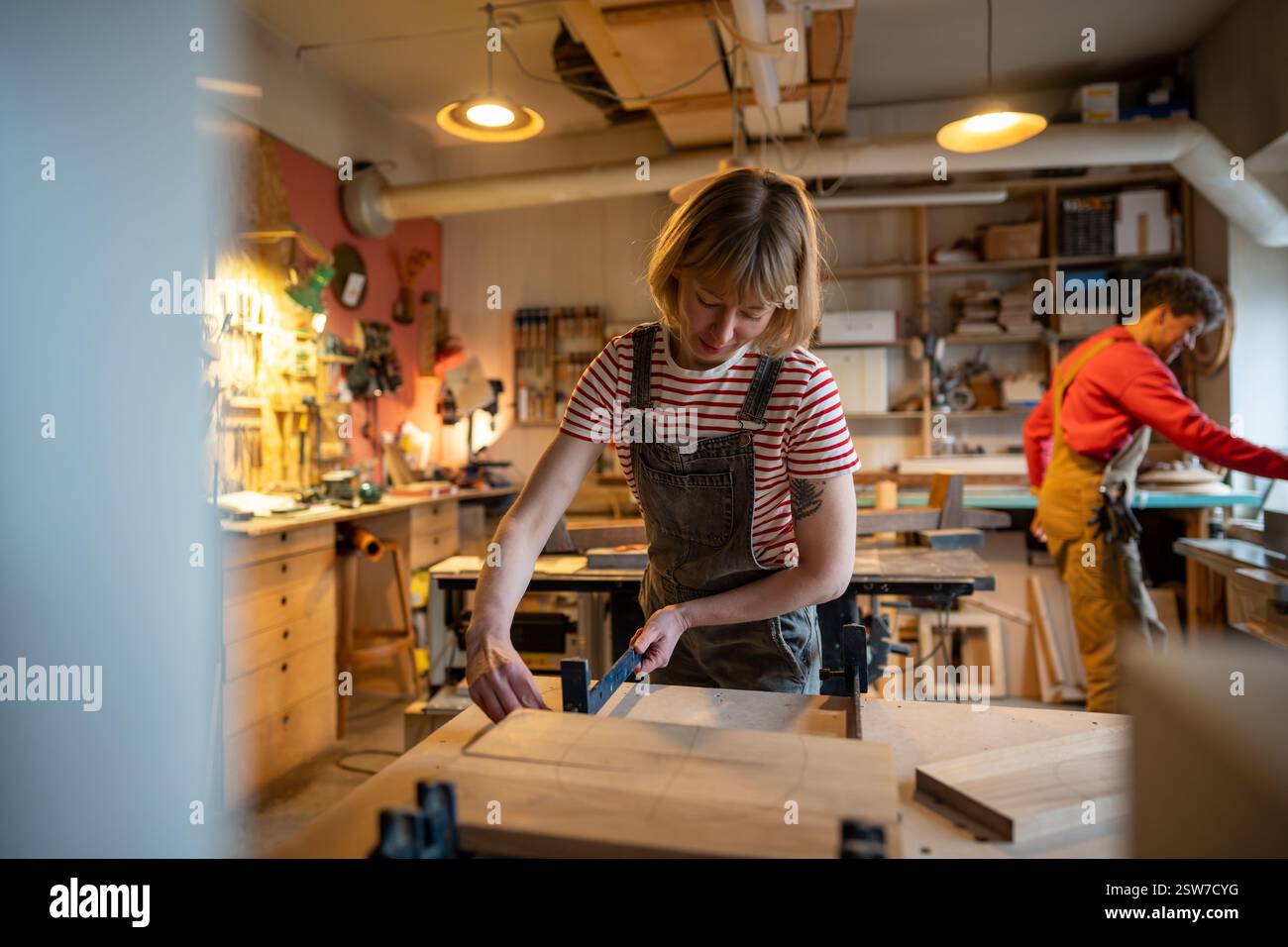 Zimmermannin bereitet Holzblöcke zum Kleben vor, Klemmen in der Holzwerkstatt. Manuelle Arbeit Stockfoto