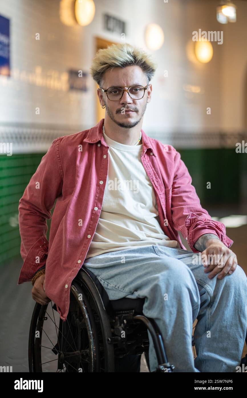 Ernsthafter Student mit Behinderung im Rollstuhl schaut in die Kamera auf dem Campus. Zugänglichkeit, barrierefrei Stockfoto