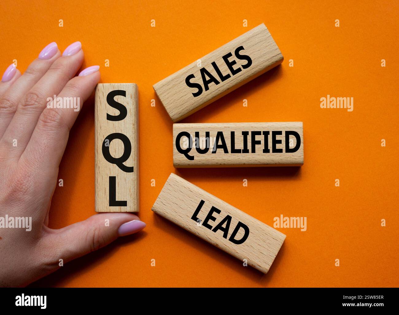 SQL - qualifizierter Lead für Vertrieb. Holzwürfel mit SQL-Wörtern. Geschäftsmann Hand. Wunderschöner orangefarbener Hintergrund. Business- und SQL-Konzept. Kopierbereich. Stockfoto