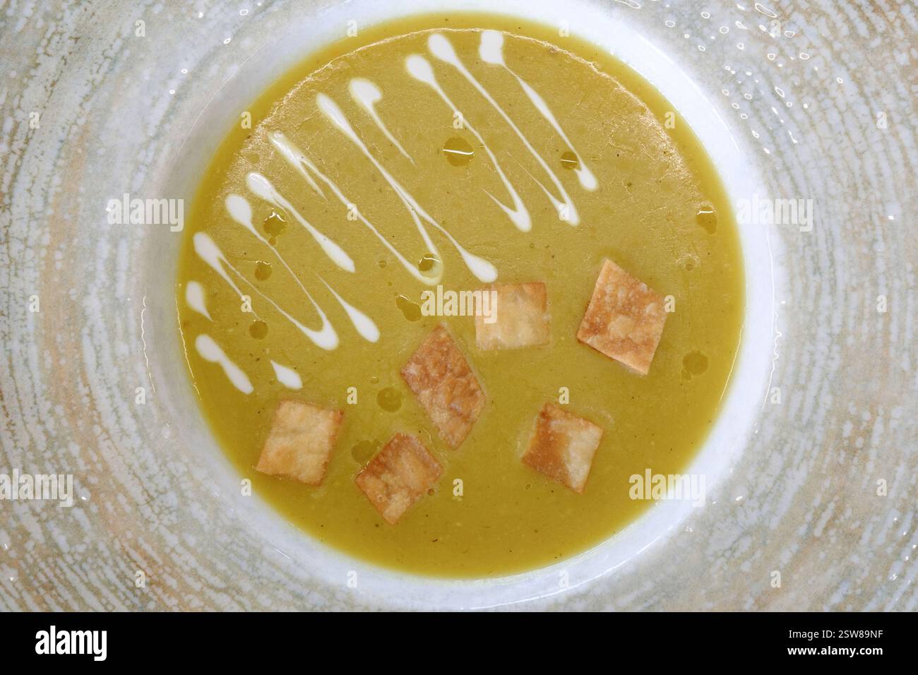 Cremige gelbe Suppe garniert mit knusprigen Croutons und einem Schuss Sahne Stockfoto
