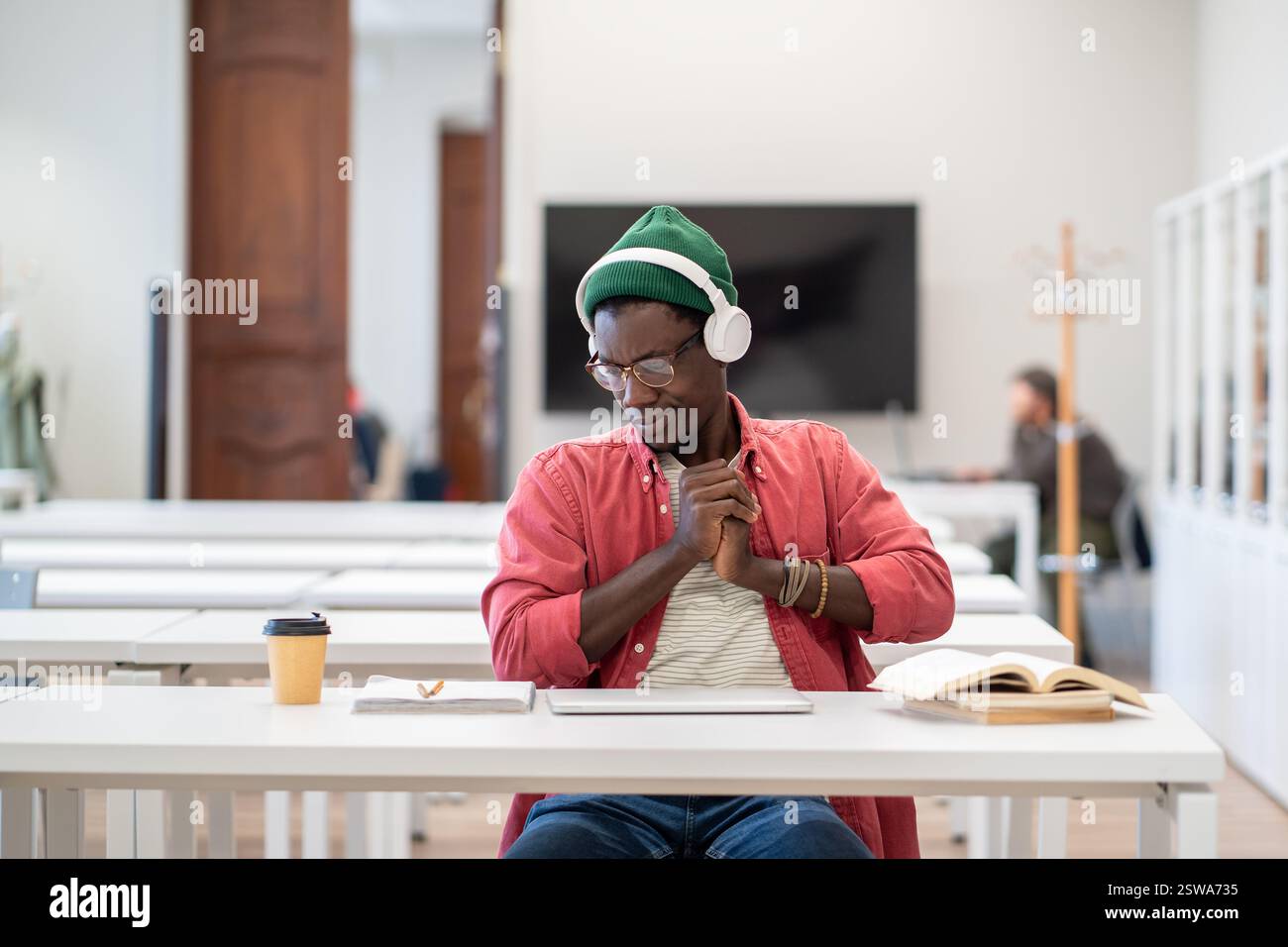 Müde, schläfrige, schwarze Studentin mit Headset Stretch auf Stuhl erschöpft nach langem Lernen am Laptop Stockfoto