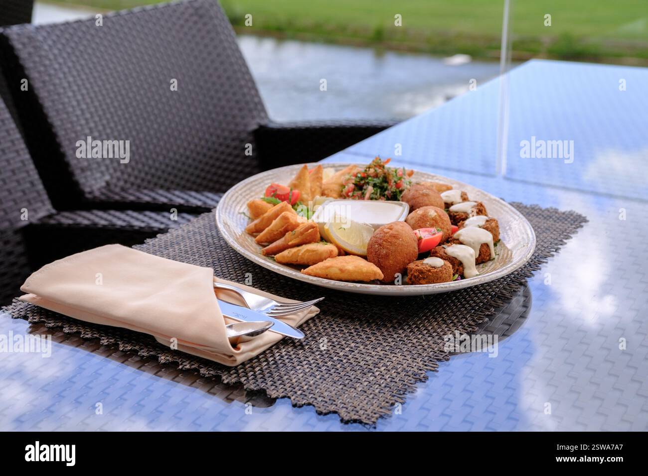 Mediterrane Vorspeisenplatte mit frittiertem Gebäck, Falafel und Dips, die draußen genossen werden Stockfoto