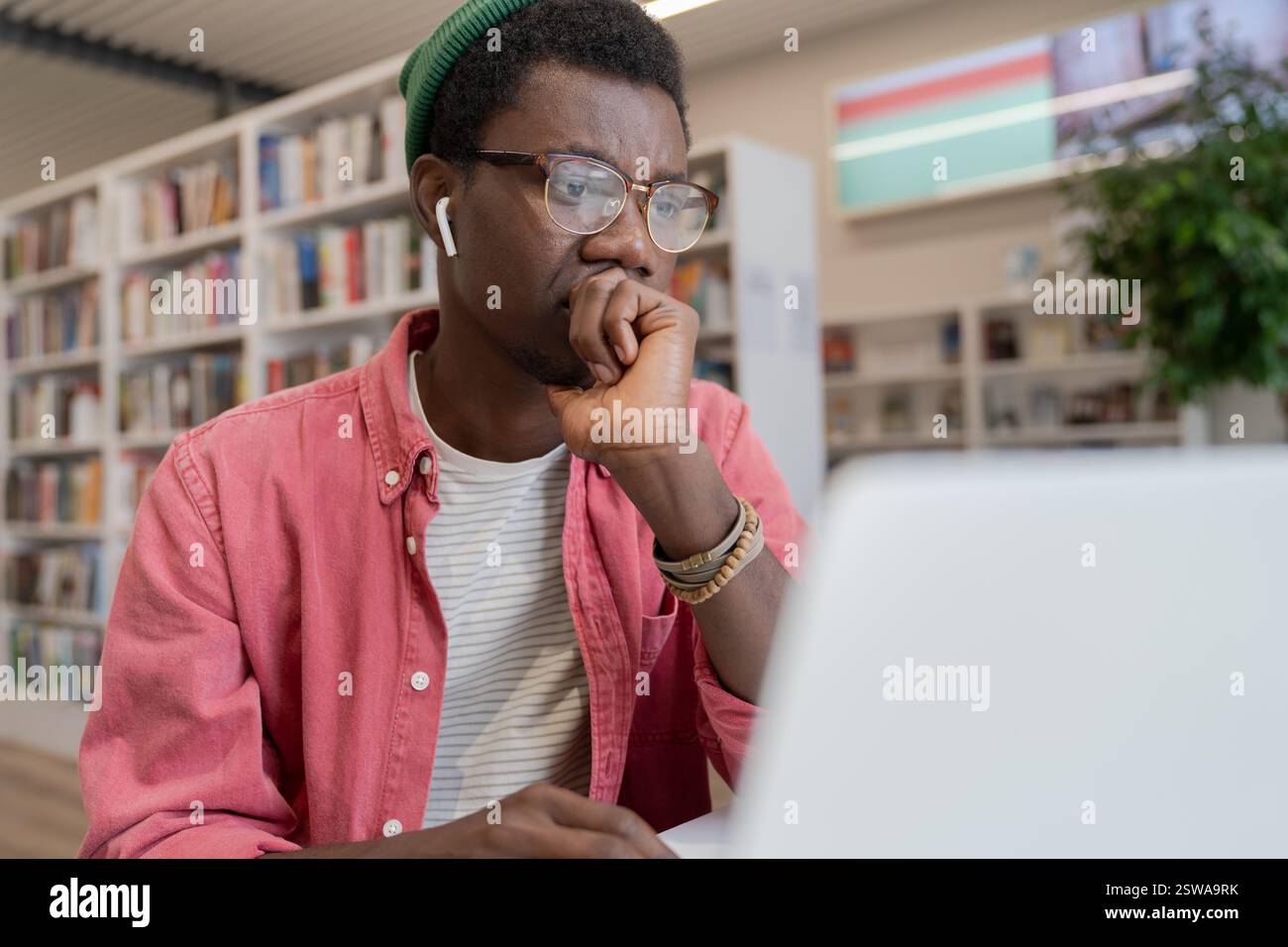 Fokussierter afroamerikanischer Schüler, der sich Online-Kurs auf einem Laptop in der Bibliothek ansieht Stockfoto