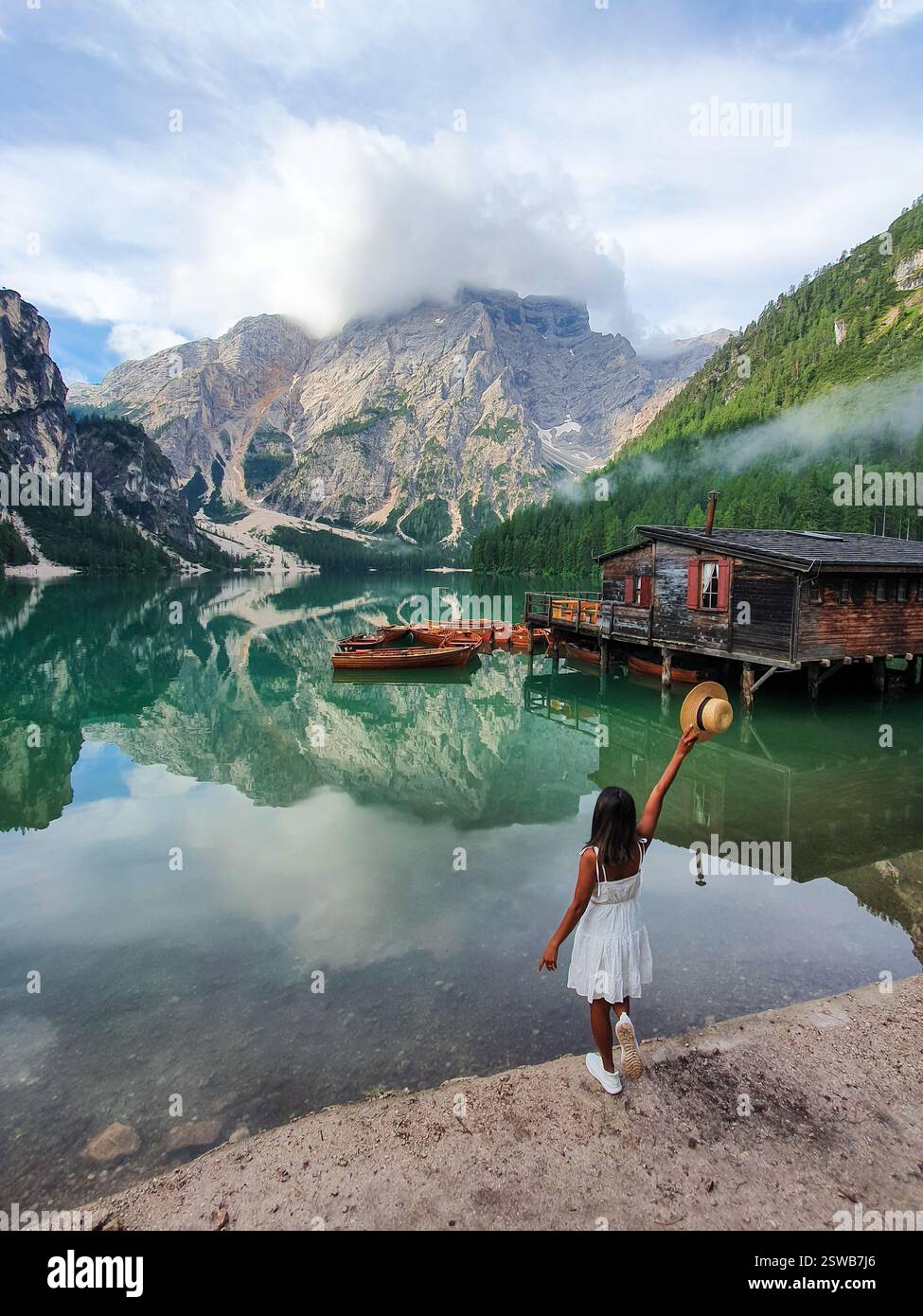Ein Mädchen in einem weißen Kleid erkundet den ruhigen See am Praies Lake unter einem bewölkten Himmel Stockfoto