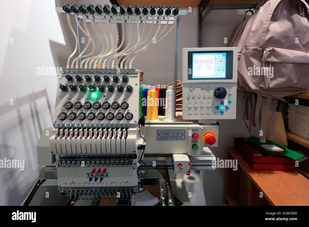 Eine kommerzielle Stickmaschine Tajima TUMX C1501 in einem Bekleidungsgeschäft. Stockfoto